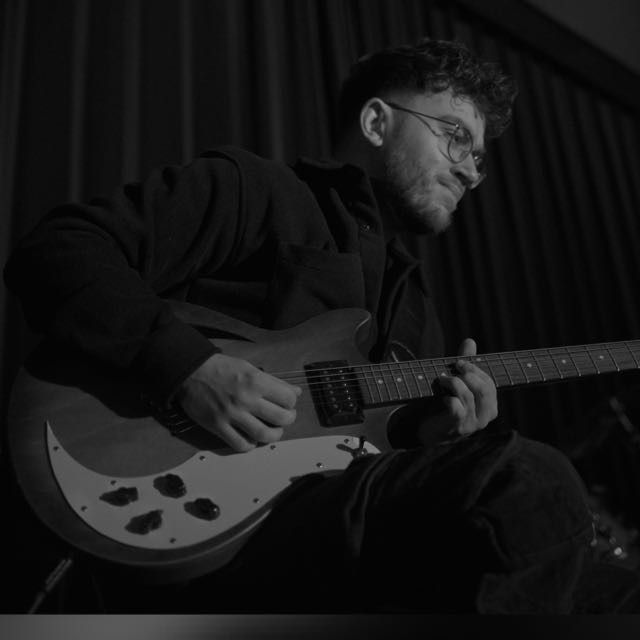Bas van Hal speelt elektrisch gitaar tijdens een zwart-witsessie